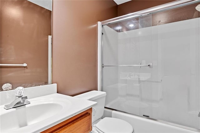 full bathroom featuring vanity, bath / shower combo with glass door, and toilet