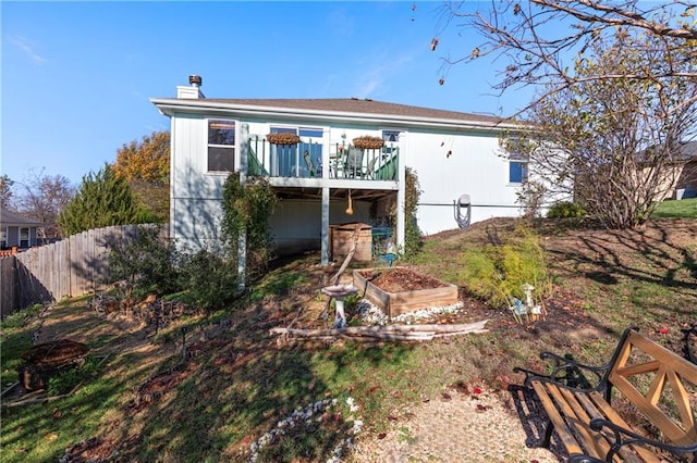 rear view of property featuring a garden, fence, a chimney, and a wooden deck