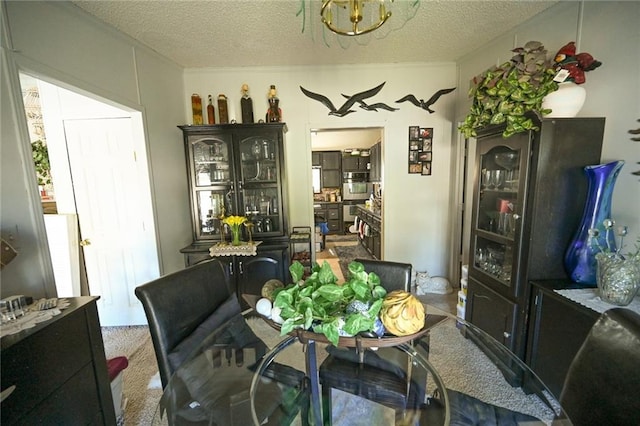 dining area featuring carpet flooring, a notable chandelier, and a textured ceiling