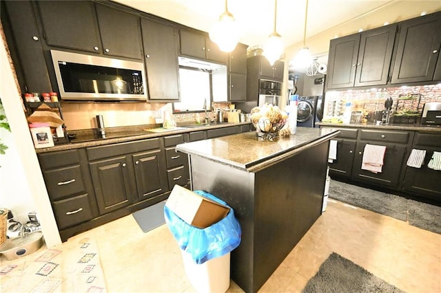 kitchen featuring black electric stovetop, backsplash, sink, decorative light fixtures, and a kitchen island