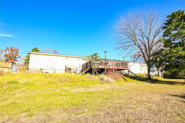 rear view of house featuring a lawn and a deck