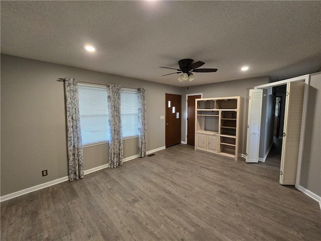 unfurnished living room featuring a textured ceiling, dark hardwood / wood-style flooring, and ceiling fan