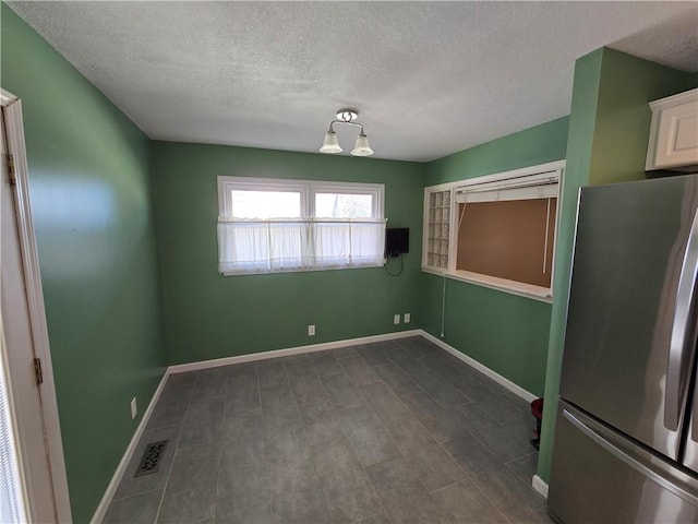 unfurnished dining area featuring a textured ceiling