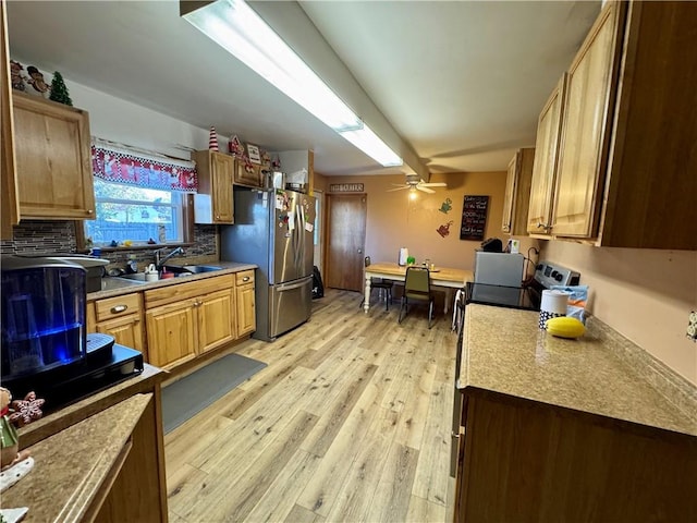 kitchen with sink, ceiling fan, light wood-type flooring, tasteful backsplash, and stainless steel refrigerator