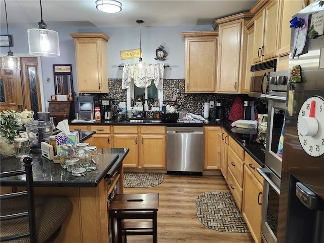 kitchen featuring sink, light hardwood / wood-style flooring, hanging light fixtures, and appliances with stainless steel finishes