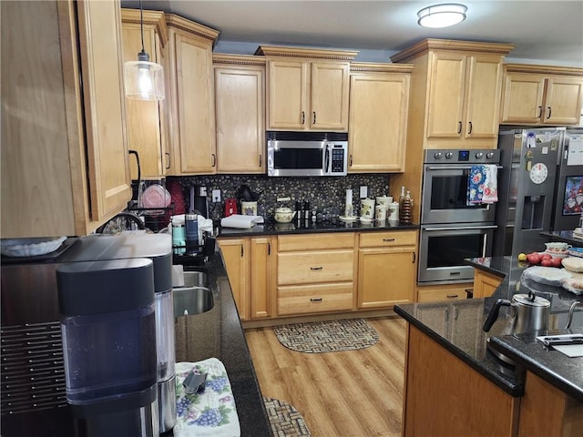 kitchen featuring hanging light fixtures, dark stone countertops, tasteful backsplash, light hardwood / wood-style floors, and stainless steel appliances