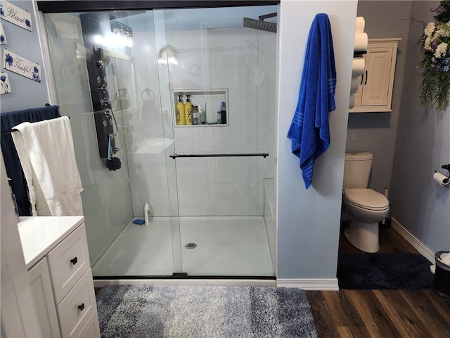 bathroom with a shower with door, vanity, wood-type flooring, and toilet