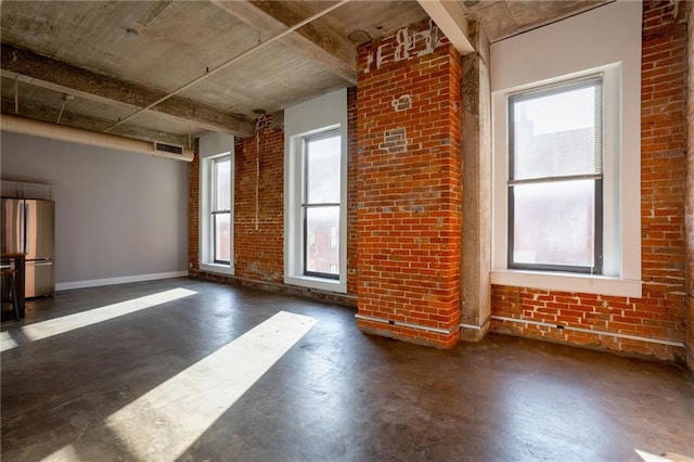 unfurnished room featuring a healthy amount of sunlight and brick wall