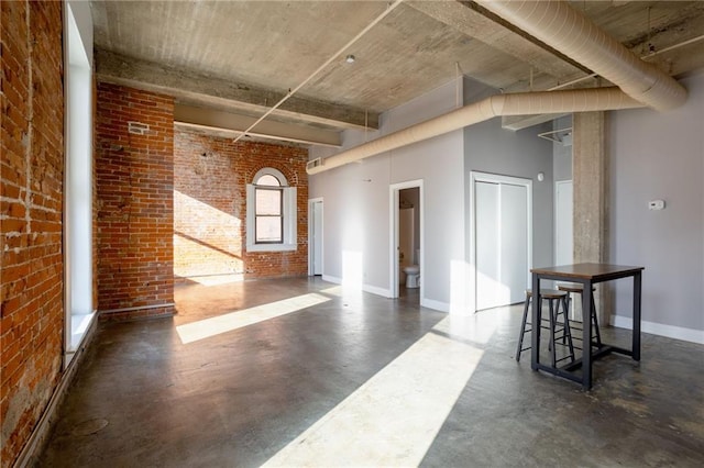 unfurnished room with a high ceiling and brick wall