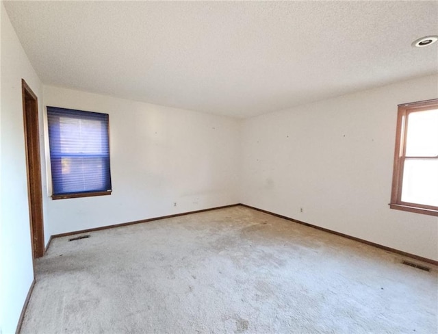 carpeted empty room with a textured ceiling