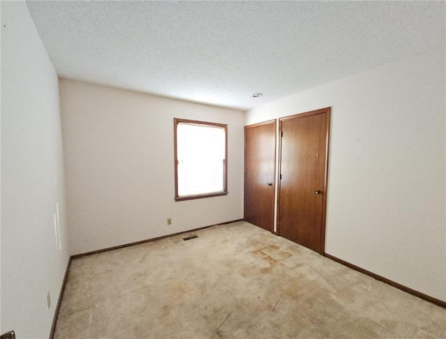 unfurnished bedroom with a textured ceiling and light colored carpet