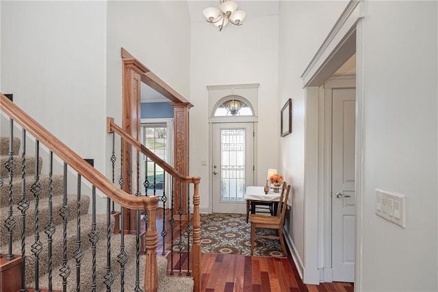 entrance foyer featuring a towering ceiling, dark wood-type flooring, and a notable chandelier