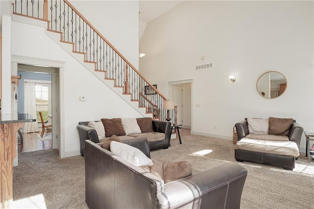 carpeted living room with high vaulted ceiling