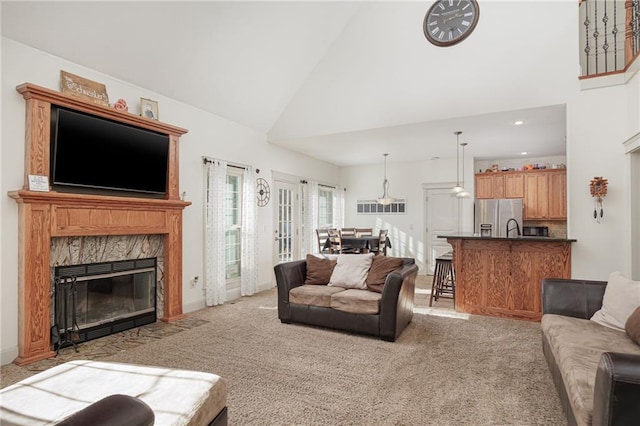 living room featuring ceiling fan, sink, high vaulted ceiling, light carpet, and a fireplace