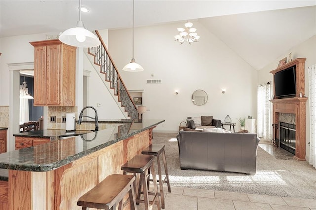 kitchen with decorative light fixtures, light colored carpet, backsplash, and high vaulted ceiling