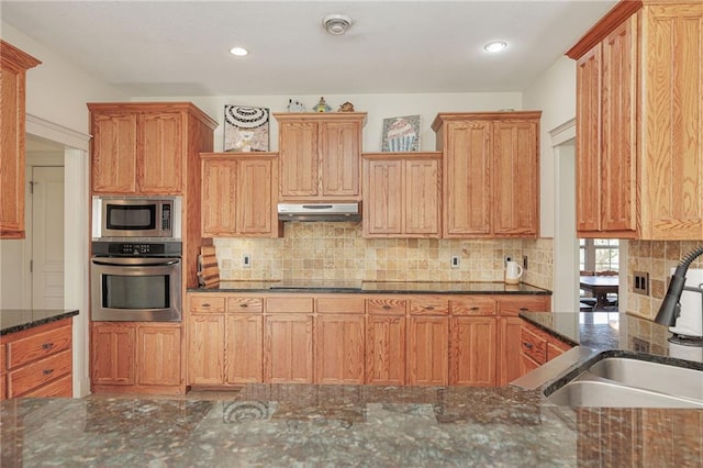 kitchen with dark stone counters, decorative backsplash, sink, and stainless steel appliances