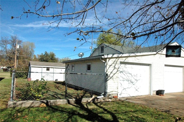 view of side of property with a lawn, a garage, and an outbuilding