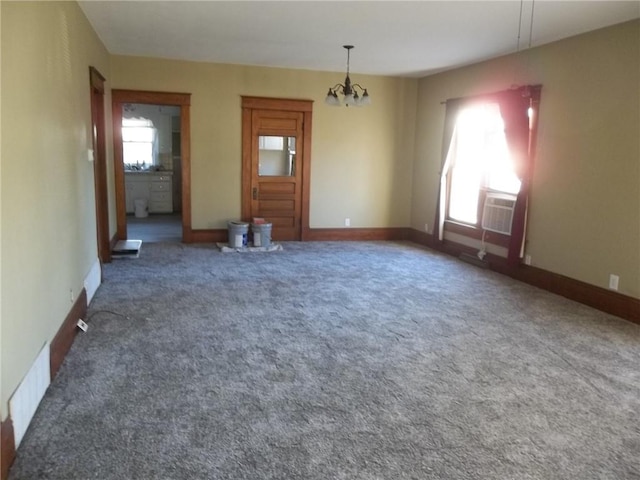 carpeted spare room with a wall mounted air conditioner, plenty of natural light, and a notable chandelier