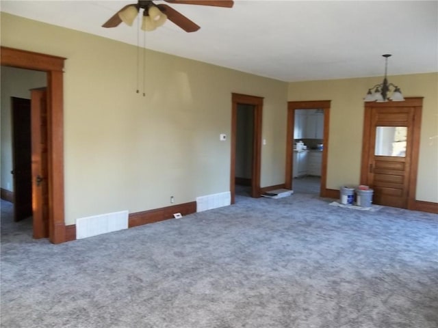 carpeted spare room with ceiling fan with notable chandelier