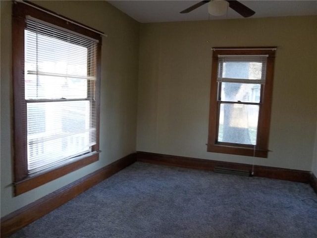 unfurnished room with ceiling fan and dark colored carpet