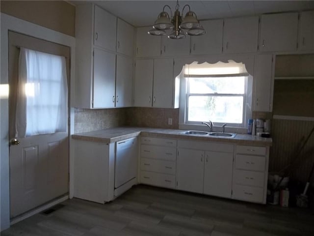 kitchen featuring white cabinetry, sink, dishwasher, a notable chandelier, and tile countertops