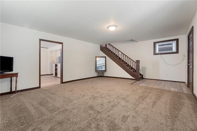 unfurnished living room with light colored carpet and an AC wall unit