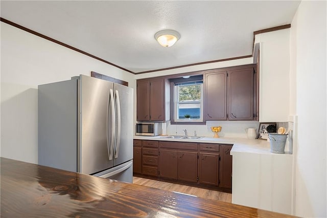 kitchen featuring crown molding, sink, appliances with stainless steel finishes, dark brown cabinets, and light hardwood / wood-style floors