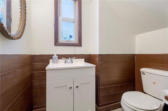 bathroom featuring vanity, toilet, and tile walls