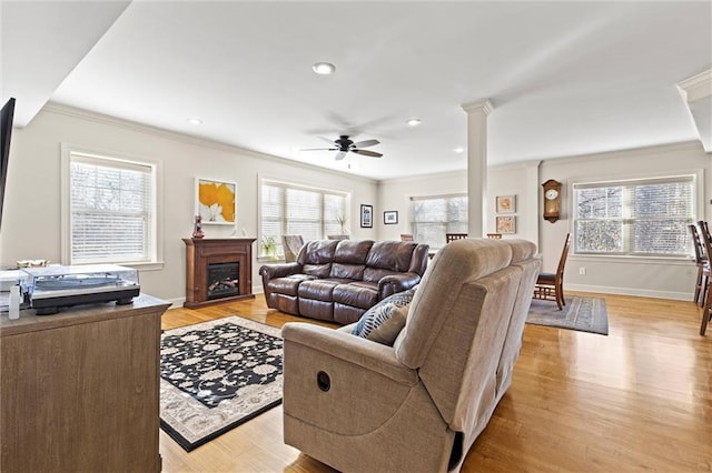 living room with ceiling fan, decorative columns, ornamental molding, and light hardwood / wood-style flooring