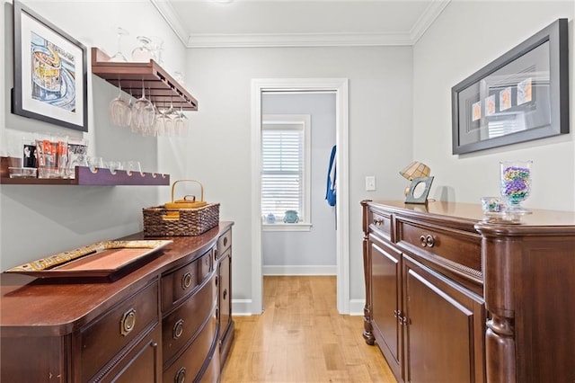 interior space featuring dark brown cabinets, ornamental molding, and light hardwood / wood-style flooring