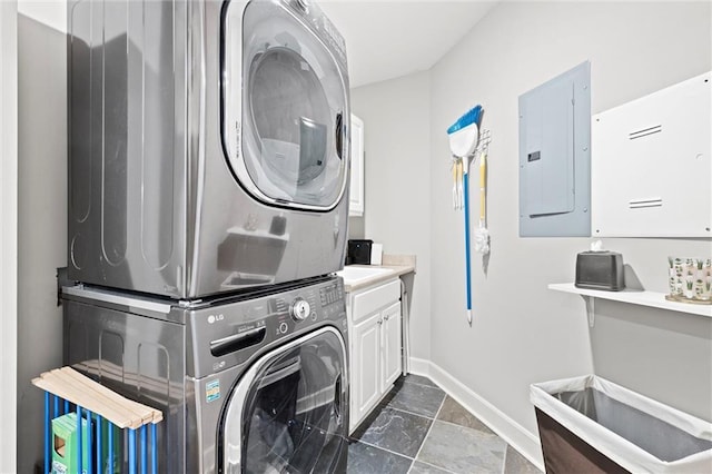 washroom with cabinets, stacked washer / drying machine, and electric panel