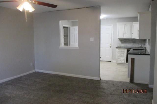 kitchen featuring carpet flooring, ceiling fan, sink, tasteful backsplash, and white cabinets