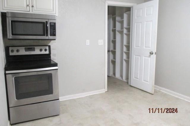 kitchen with light carpet, white cabinets, and appliances with stainless steel finishes