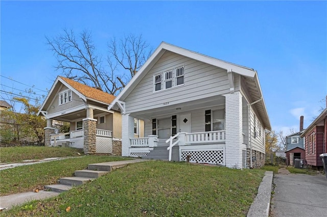 bungalow with cooling unit, a porch, and a front lawn