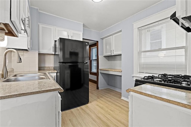 kitchen with a wealth of natural light, sink, white cabinets, and black appliances