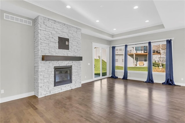 unfurnished living room featuring a fireplace, dark hardwood / wood-style floors, and a tray ceiling