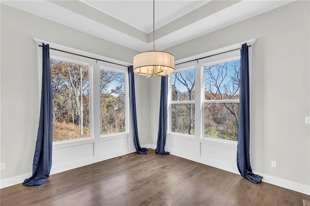 unfurnished dining area featuring a wealth of natural light, dark hardwood / wood-style floors, and an inviting chandelier