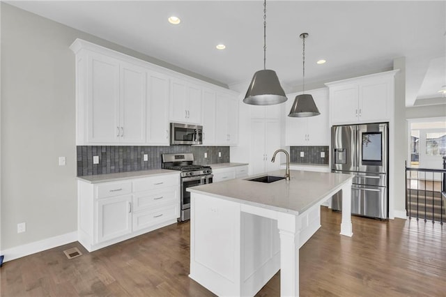 kitchen with pendant lighting, a center island with sink, sink, white cabinetry, and stainless steel appliances