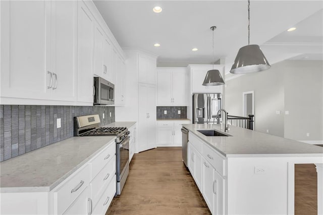 kitchen featuring tasteful backsplash, stainless steel appliances, sink, pendant lighting, and an island with sink