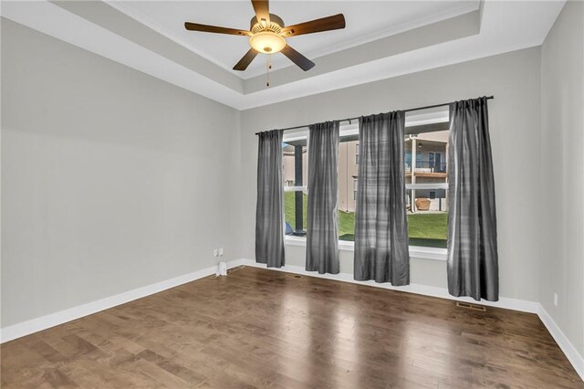 unfurnished room with ceiling fan, a raised ceiling, wood-type flooring, and crown molding