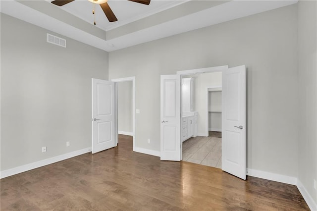 4520 NW 49th Ct, Riverside, MO 64150 - unfurnished bedroom with baseboards, a tray ceiling, and wood finished floors