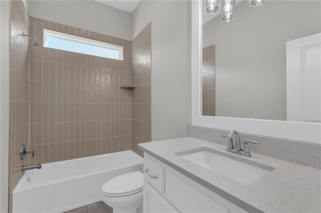 full bathroom featuring vanity, tiled shower / bath combo, and toilet