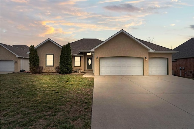 ranch-style home featuring stucco siding, a yard, concrete driveway, and an attached garage