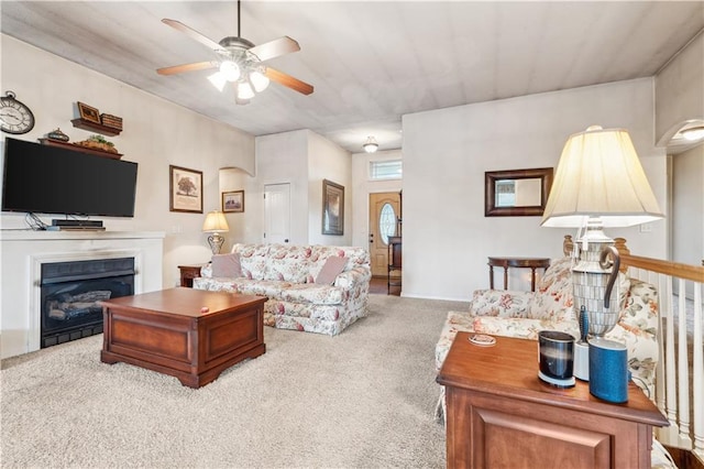 living area featuring a fireplace, carpet, and a ceiling fan