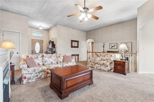 carpeted living area with arched walkways and ceiling fan