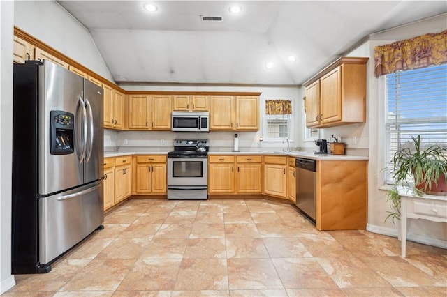 kitchen featuring stainless steel appliances, light countertops, lofted ceiling, and a sink