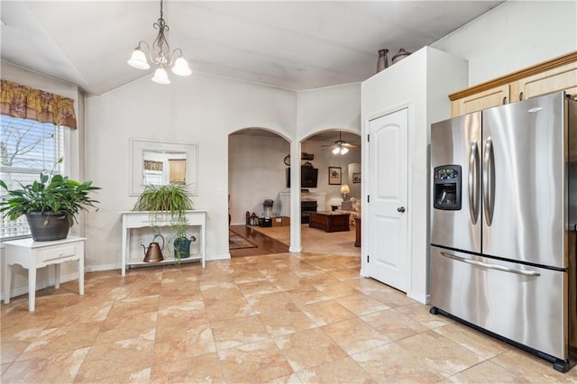 kitchen with stainless steel fridge with ice dispenser, pendant lighting, vaulted ceiling, ceiling fan with notable chandelier, and arched walkways