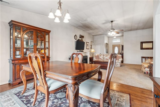 dining area with hardwood / wood-style floors, ceiling fan with notable chandelier, and visible vents