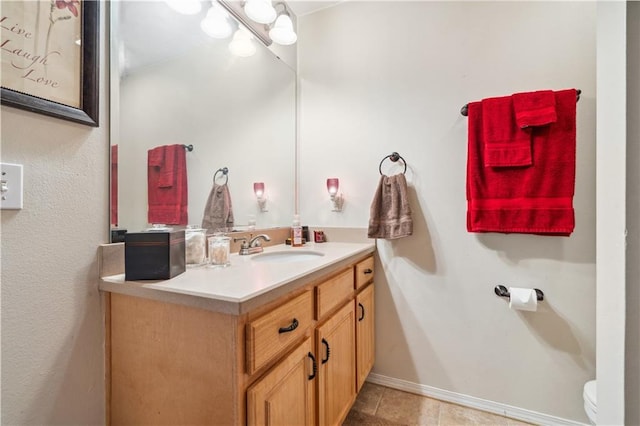 half bath featuring tile patterned floors, baseboards, toilet, and vanity