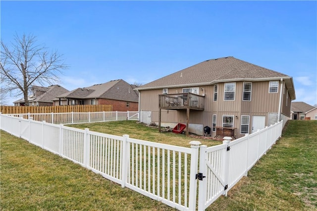 rear view of house featuring a lawn, a fenced backyard, and a gate